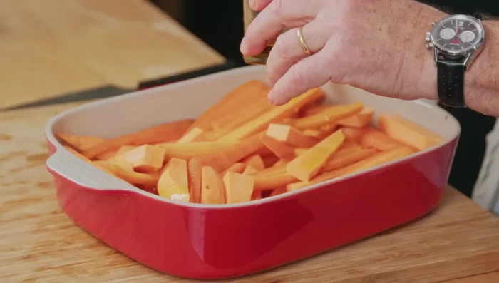 Mélanger les carottes et les patates douces dans un plat à four. Assaisonner avec de l'huile d'olive, du sel et du poivre.