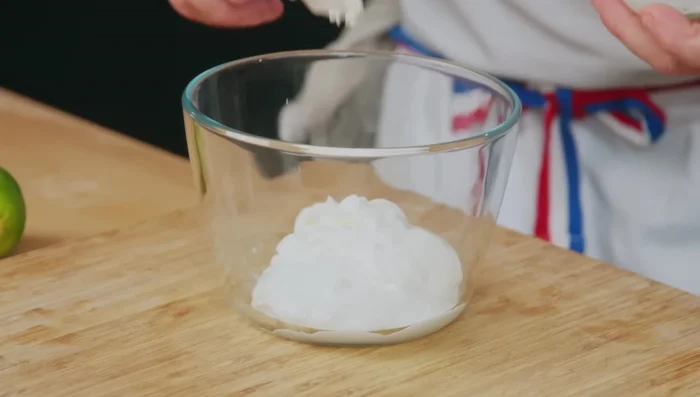 Pendant la cuisson du poulet, préparer la sauce : mélanger le fromage frais avec du sel, du zeste et du jus de citron vert, et du tendori (ou autre épice).