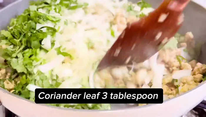 Ajouter l'oignon haché et la coriandre fraîche au poulet.