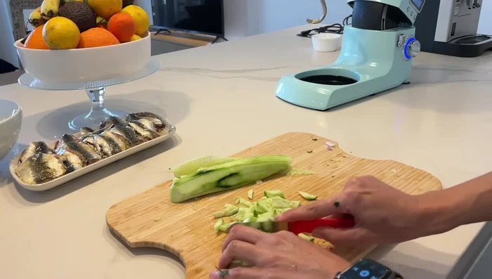 Préparation d'une salade simple : Mélanger des tomates, des concombres, de la coriandre, de l'oignon rouge, du sel, du poivre, du citron et de l'huile d'olive. Réserver au frais.