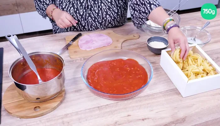 Disposez les nids de pâtes secs dans la sauce tomate au fond du plat à gratin.