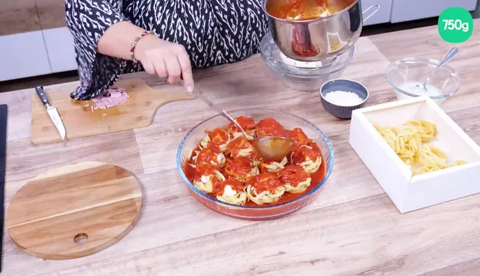 Couvrez avec le reste de la sauce et ajoutez quelques cuillères à soupe d'eau de mozzarella.