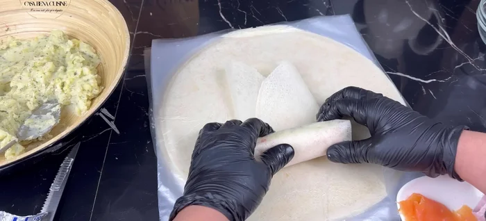 Plier les côtés de la feuille de brick et rouler fermement. Utiliser un peu de blanc d’œuf ou une colle alimentaire pour sceller.