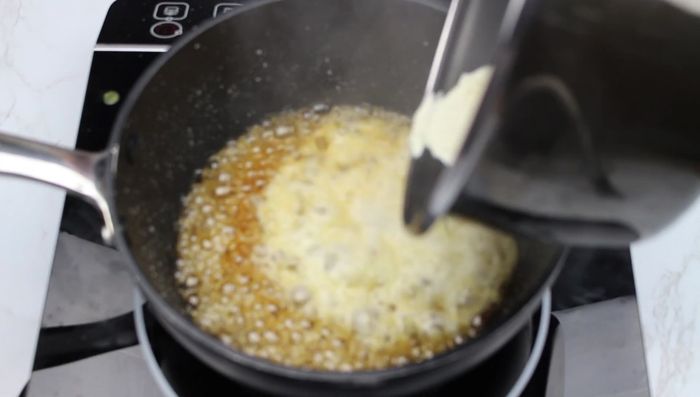 Une fois le caramel prêt, verser la crème en filet, en mélangeant avec une spatule.