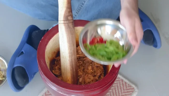 Ajouter les piments frais tranchés (facultatif), une autre cuillère à soupe de poudre de piment grillé et la peau de poulet réservée.