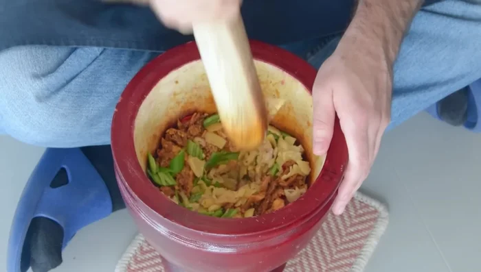 Piler le tout soigneusement pendant quelques minutes, jusqu'à ce que les piments soient bien brisés.