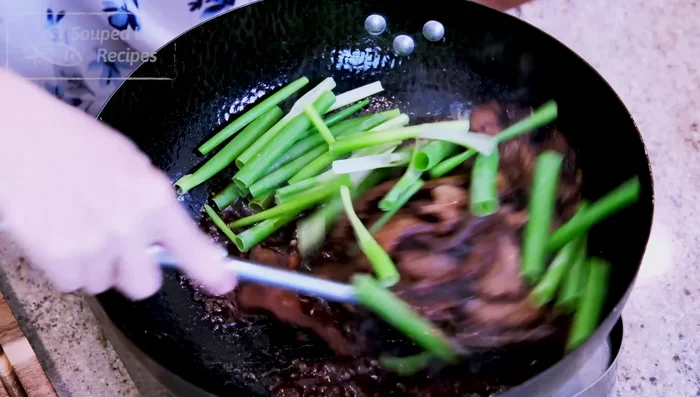 Finir la cuisson : Remettre le bœuf dans la marmite avec la partie verte des oignons verts. Mélanger jusqu'à ce que la viande soit bien enrobée de sauce.