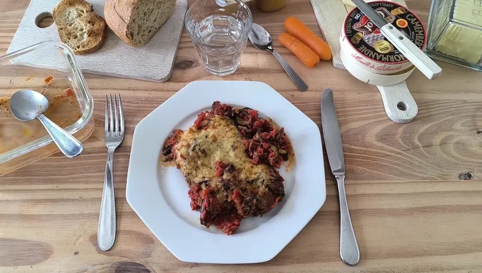 Dans un plat à gratin, superposer des couches de courgettes, de tomates, de bœuf haché, d'herbes et de fromage.