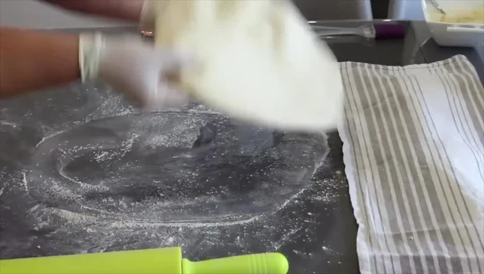 Étaler chaque pâton finement, étaler du beurre fondu sur toute la surface, rouler en escargot, puis aplatir légèrement.
