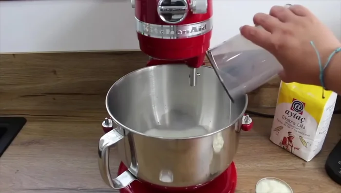 Préparer la pâte : mélanger le lait, le yaourt, le sel, la levure chimique et la farine jusqu'à obtenir une pâte légèrement collante.