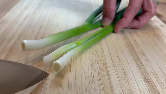 Couper 2 oignons verts en deux dans le sens de la longueur, puis en tronçons de 5 cm.