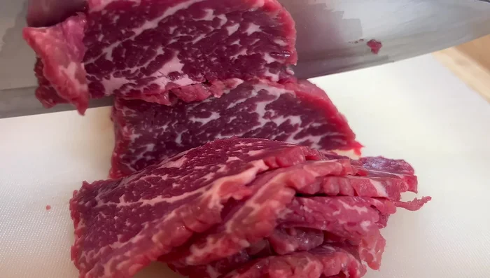 Couper le bœuf en tranches contre le sens des fibres. Faire mariner avec de la sauce soja, de la sauce soja noire, du sucre, du bicarbonate de soude, de l'eau et de la fécule de maïs. Bien mélanger.
