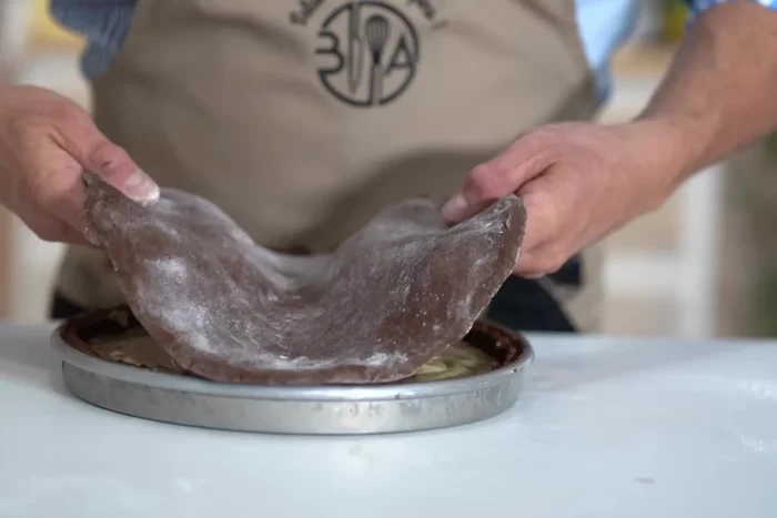Recouvrir de la pâte à gâteau basque au chocolat restante. Fermer le gâteau et retirer l'excédent de pâte.