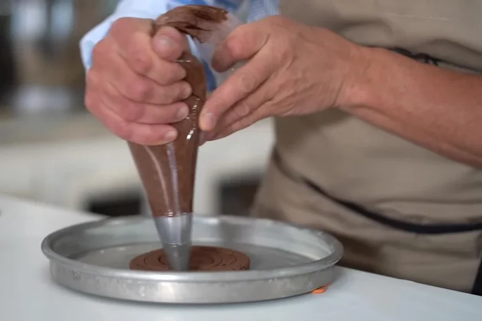 Verser la moitié de la pâte dans un moule à gâteau graissé (ou un moule à pizza). Étaler la pâte sur le fond et faire une bordure en lissant avec le dos d'une cuillère à café. Retirer l'excédent de pâte.