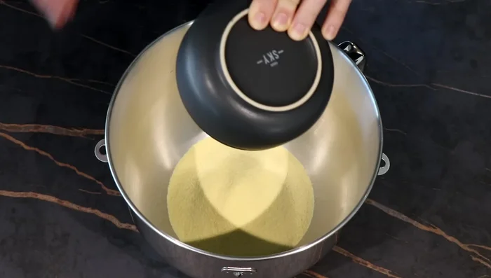 Dans le bol du robot, verser la semoule, 150g de farine, le sucre, le sel. Mélanger.