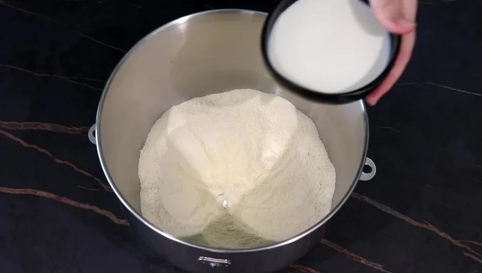 Creuser un puits, ajouter le lait tiède, le blanc d’œuf, l’œuf entier, le mélange à la levure et l’huile. Pétrir 5 minutes (robot ou à la main).
