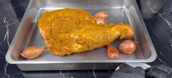 Disposer les oignons, les échalotes, les gousses d'ail et les piments autour de l'épaule d'agneau dans un plat allant au four.