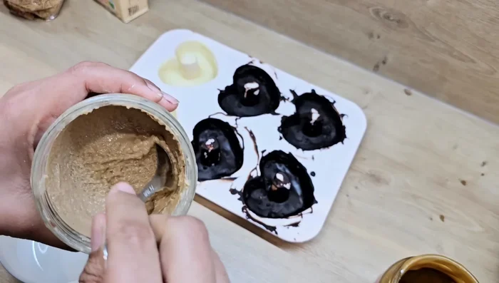 Préparation optionnelle : Faire chauffer légèrement la pâte à tartiner noisette chocolat blanc. Mélanger avec des cadaïf et de la poudre de biscuits. Remplir d’autres moules avec ce mélange et recouvrir de chocolat blanc.