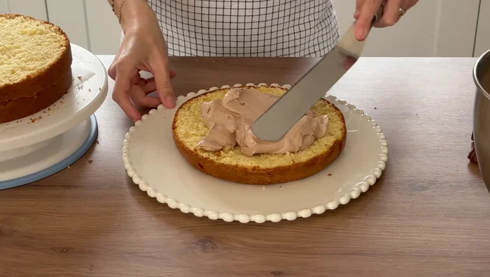 Montage du gâteau: Étaler une couche de crème sur le premier disque de Molly cake, ajouter des morceaux de Kinder Bueno, puis recouvrir avec le deuxième disque et répéter l'opération.