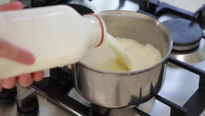 Préparation du lait aromatisé : Dans une casserole, chauffer le lait avec des oignons hachés, une feuille de laurier, du thym, du sel, du poivre blanc et de la muscade râpée. Porter à frémissement, puis retirer du feu.