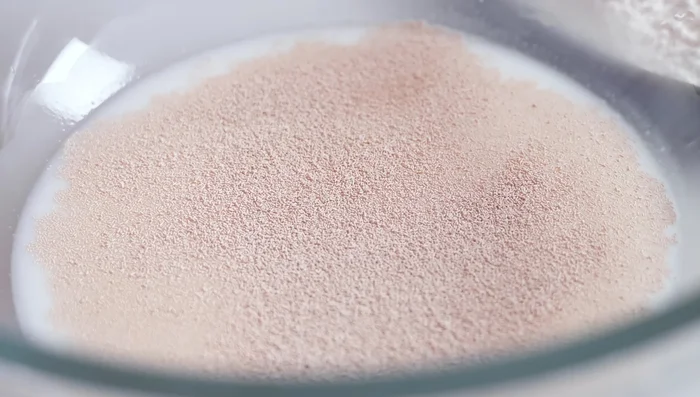 Dans un bol, mélanger le lait chaud, l'eau tiède, la levure, 1 cuillère à café de sucre (sur les 30g) et 5 cuillères à soupe de farine. Couvrir et laisser reposer 15 minutes dans un endroit chaud.