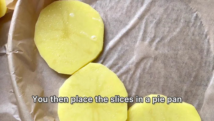 Disposer les rondelles dans un moule à tarte chemisé de papier cuisson, en recouvrant bien le fond.