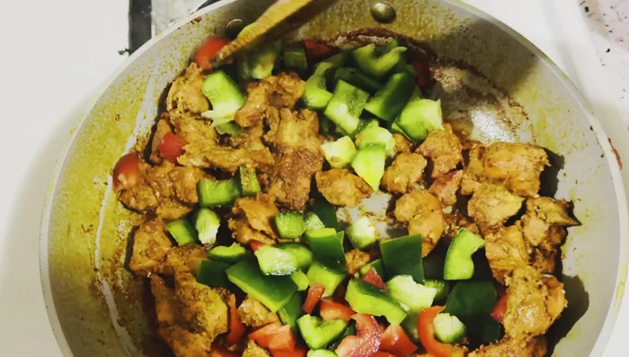 Ajouter les poivrons et les oignons au poulet, mélanger et cuire sans trop cuire les légumes.