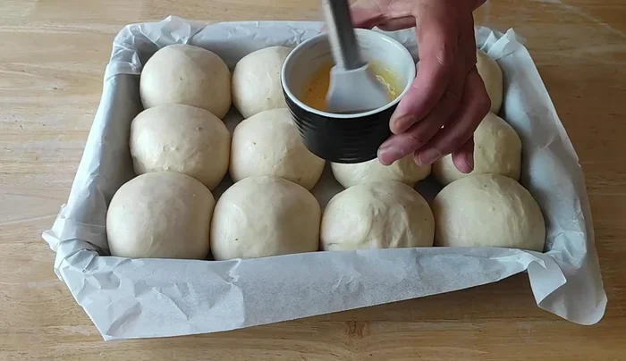 Badigeonner les brioches avec un mélange de jaune d’œuf et de lait.