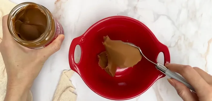 Préparation de la ganache spéculoos : Mélanger de la pâte de spéculoos avec de la crème liquide chaude jusqu'à obtenir une consistance homogène.