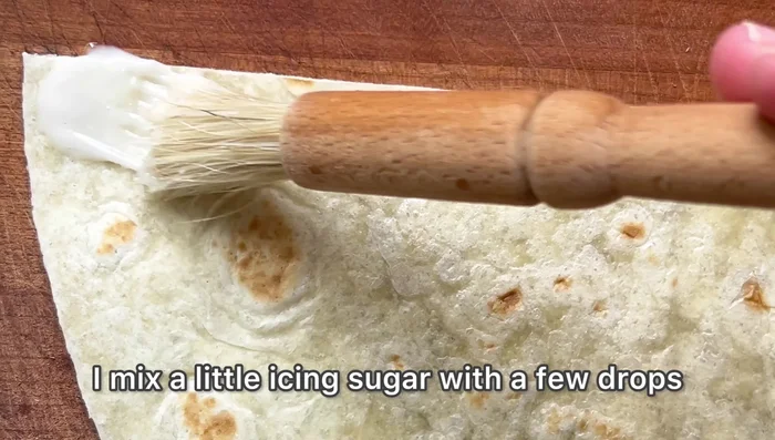 Mélangez du sucre glace avec quelques gouttes d'eau pour faire une colle alimentaire (97.72).