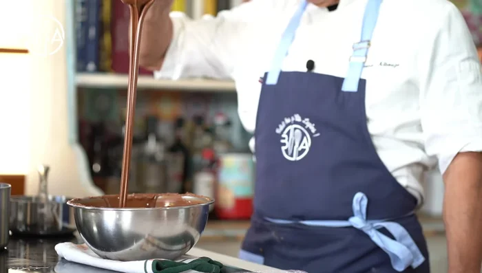 Préparez la coque en chocolat : Utilisez un système de pulvérisation à compresseur pour appliquer un film de beurre de cacao tempéré ou un mélange de chocolat et de beurre de cacao sur votre moule à chocolat. Ici, un mélange de beurre de cacao et de chocolat noir rouge est utilisé.