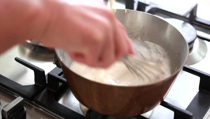 Faire épaissir la Béchamel : Cuire la béchamel à feu moyen-doux en fouettant constamment jusqu’à ce qu’elle épaississe et ait la consistance d’une pâte. (330.479)