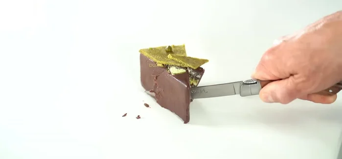 Préparer l’aragé au chocolat : Mélanger le beurre de cacao fondu avec le chocolat noir, passer au tamis et tremper chaque gâteau congelé dans le chocolat. (12.48)