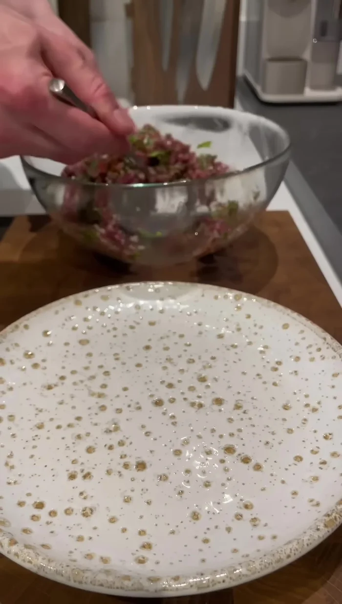 Dresser le tartare : former une bande de tartare, déposer un jaune d'œuf dessus, saler (au dernier moment).