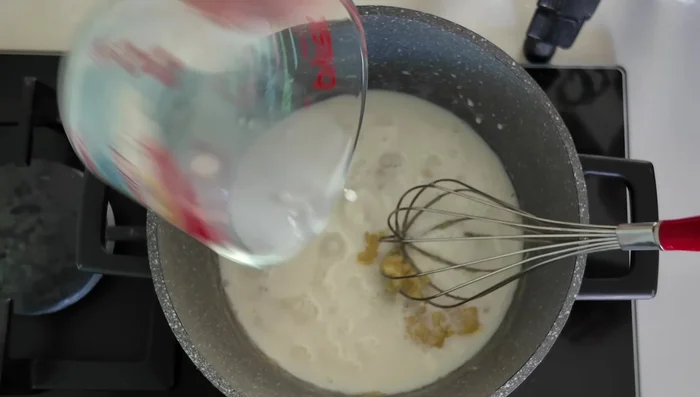 Ajouter le lait, augmenter légèrement le feu (doux/moyen), et mélanger jusqu'à épaississement de la béchamel.