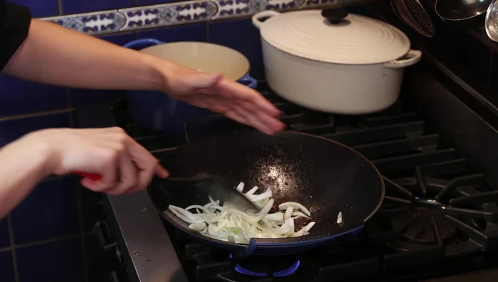 Ajouter l'oignon dans le wok et faire revenir pour décoller les saveurs.