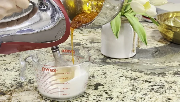 Verser lentement le sirop chaud sur les blancs d'œufs en fouettant continuellement pendant 4 à 5 minutes jusqu'à obtenir une meringue brillante et ferme.