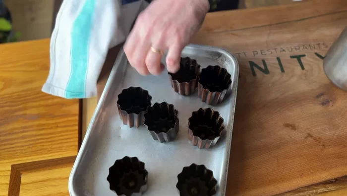 Verser la pâte dans les moules : Remplir les moules à canelés pré-cirés avec la pâte, en laissant environ 1 cm d'espace en haut.