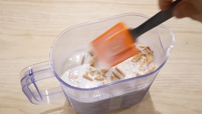Dans un grand pichet, mélangez les biscuits écrasés avec 0.5L de lait. Laissez reposer quelques minutes pour que les biscuits s'imbibent.