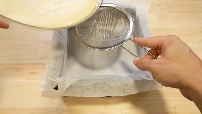 Verser la préparation dans un moule recouvert de papier cuisson. Passer au tamis pour enlever les bulles (facultatif).