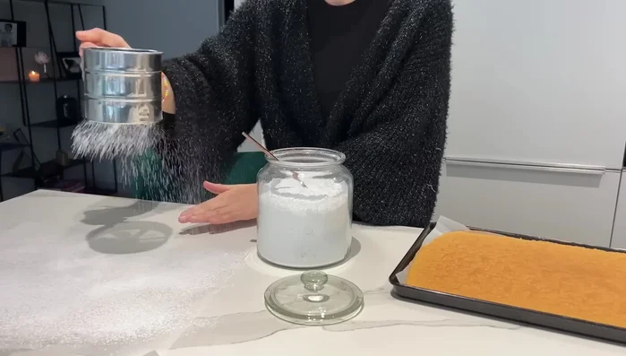 Enrouler la génoise chaude dans du papier sulfurisé saupoudré de sucre glace.
