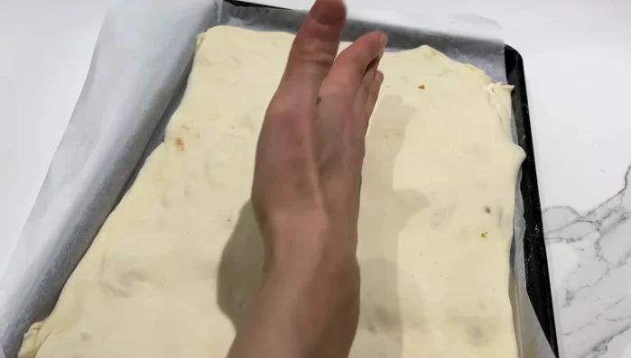 Marquer la pâte, badigeonner de lait, ajouter du fromage, des graines de sésame et de nigelle.