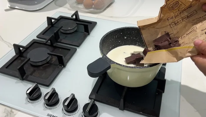 Préparer le chocolat chaud : Faire bouillir le lait et la crème liquide. Ajouter le chocolat noir, mélanger.