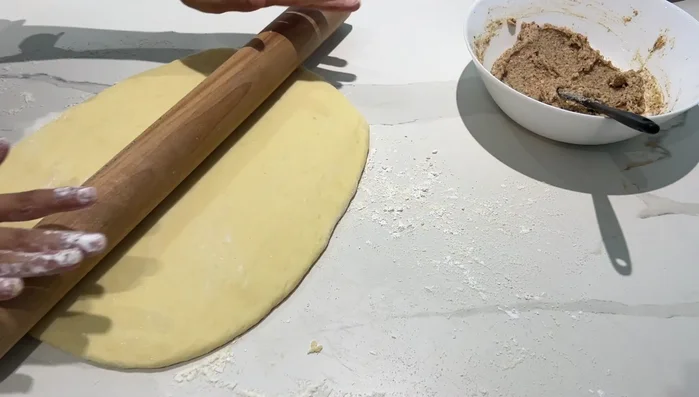 Étaler la pâte à brioche, étaler la crème d'amande, replier la pâte, et former des escargots.