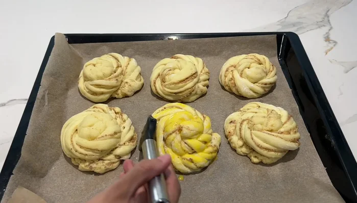 Badigeonner les brioches de lait et jaune d'œuf, ajouter les fruits rouges, et enfourner à 180°C pendant 15-20 minutes.