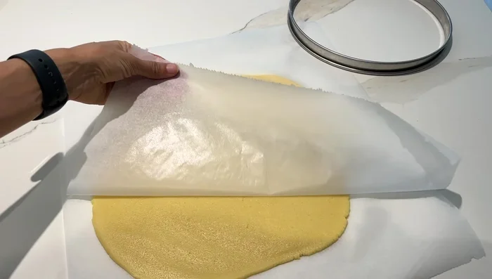 Étaler la pâte entre deux feuilles de papier sulfurisé et la placer dans un cercle à pâtisserie. Piquer la pâte à la fourchette.