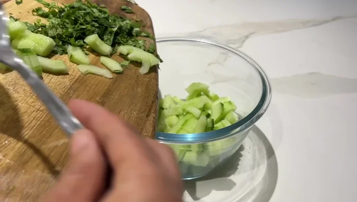 Préparation de la salade concombre : Mélanger le concombre émincé, le persil, la coriandre, le sel, le poivre et le fromage blanc. Réfrigérer quelques heures.