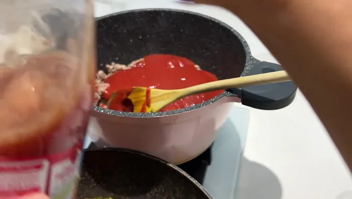 Préparation de la sauce tomate pour les lasagnes : Ajouter de la sauce tomate, de la purée de tomate et du concentré de tomate. Laisser mijoter 15-20 minutes pour épaissir. Ajouter du persil.