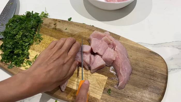 Préparation des escalopes : Préparer 500g d'escalopes avec du persil, de la coriandre, des poivrons rouges coupés, de l'huile d'olive, du sel, du poivre, du paprika et du gingembre. (Variante au curry possible avec lait/crème de coco).