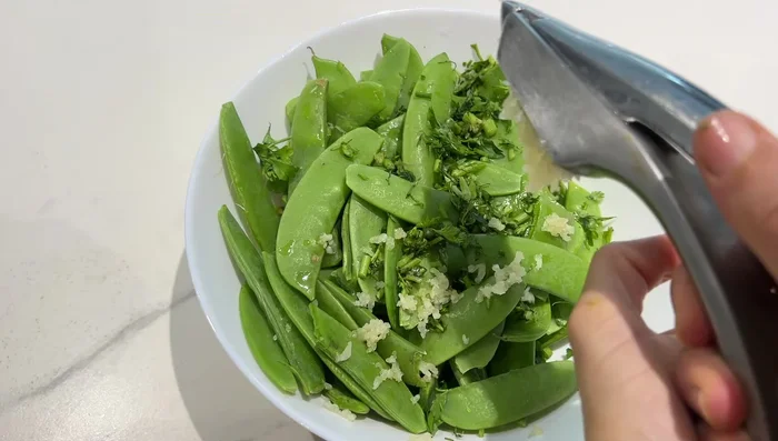 Préparation des poids gourmands : Laver et essorer les poids gourmands. Ajouter du persil, de la coriandre, de l'ail, du sel, du poivre et de l'huile d'olive. Mélanger.